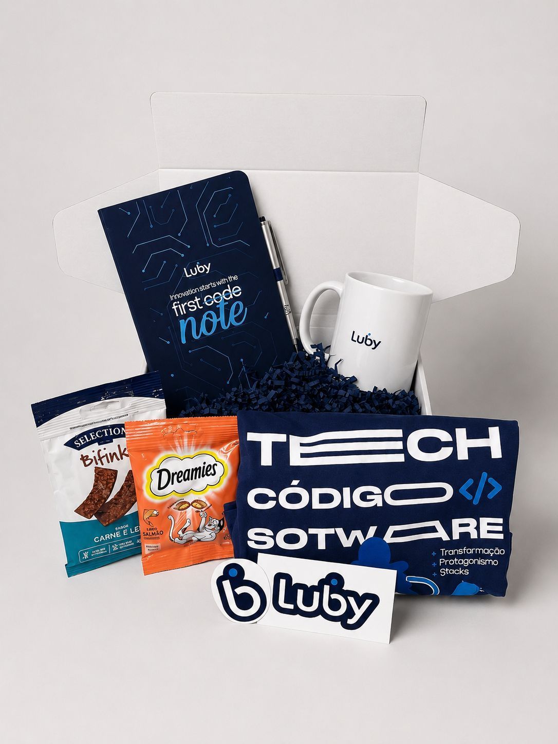 Promotional tech kit with notebook, mug, snacks, and a navy “TECH CÓDIGO SOFTWARE” sign on a white backdrop