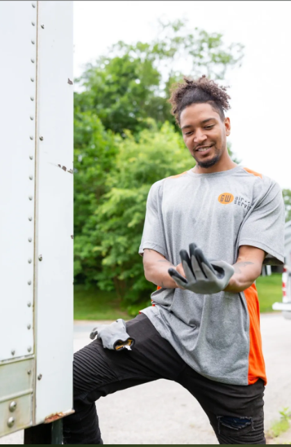 Worker in gray shirt and black gloves loading cargo beside a truck outdoors