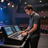 Man adjusting controls on a digital mixing console in a dimly lit theater auditorium