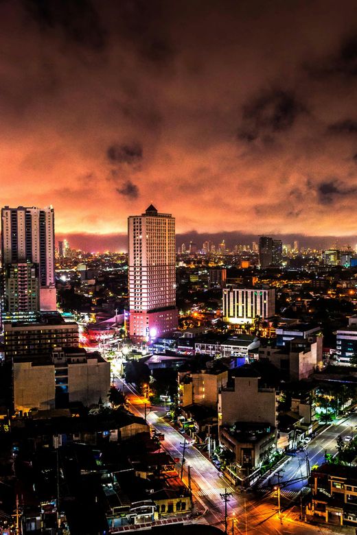City skyline at night with glowing buildings under a dramatic orange sky