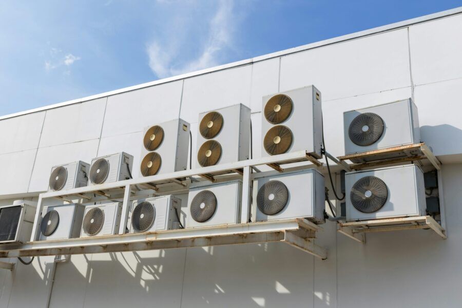 White air conditioning units mounted on the side of a building, under a blue sky. San Jose's Best Commercial HVAC Business.