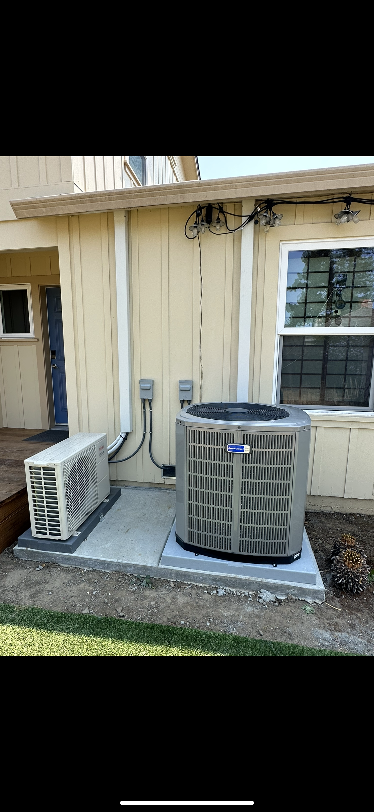 Air conditioning units on a concrete pad next to a house.
