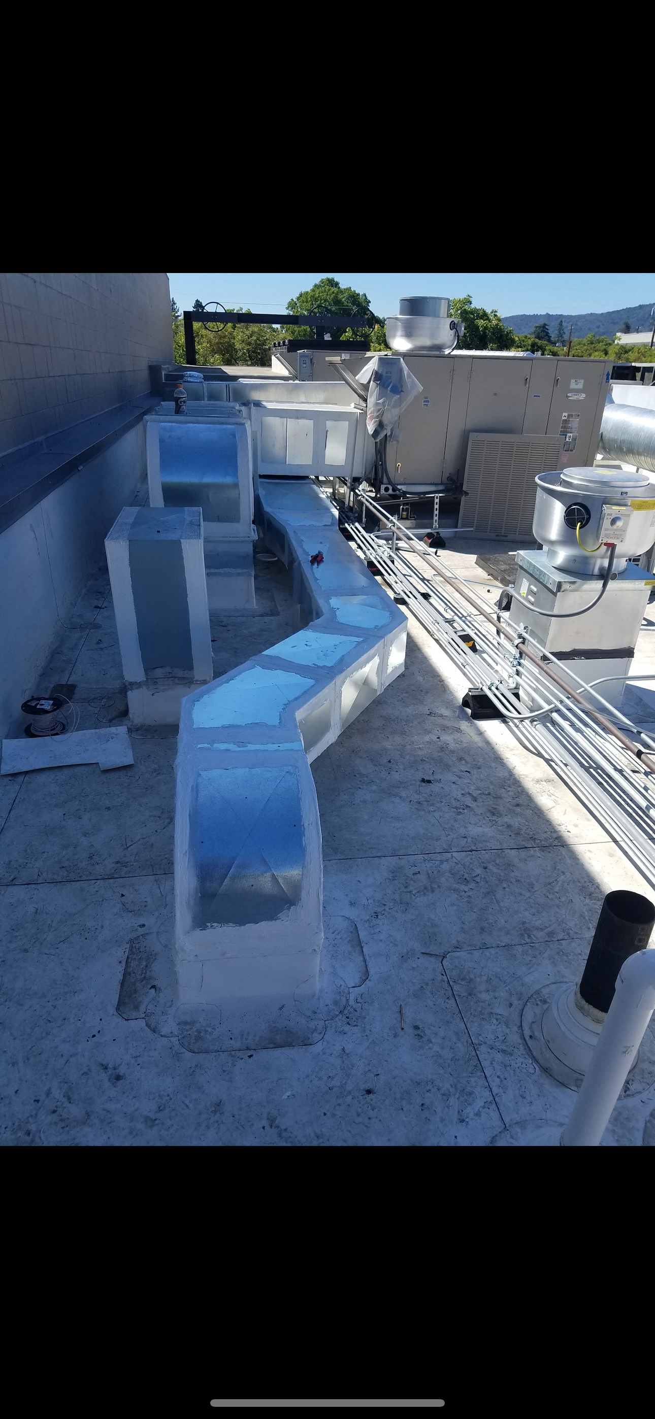 HVAC ductwork on a rooftop. The ductwork is silver and zigzags across the roof, with other mechanical equipment visible.