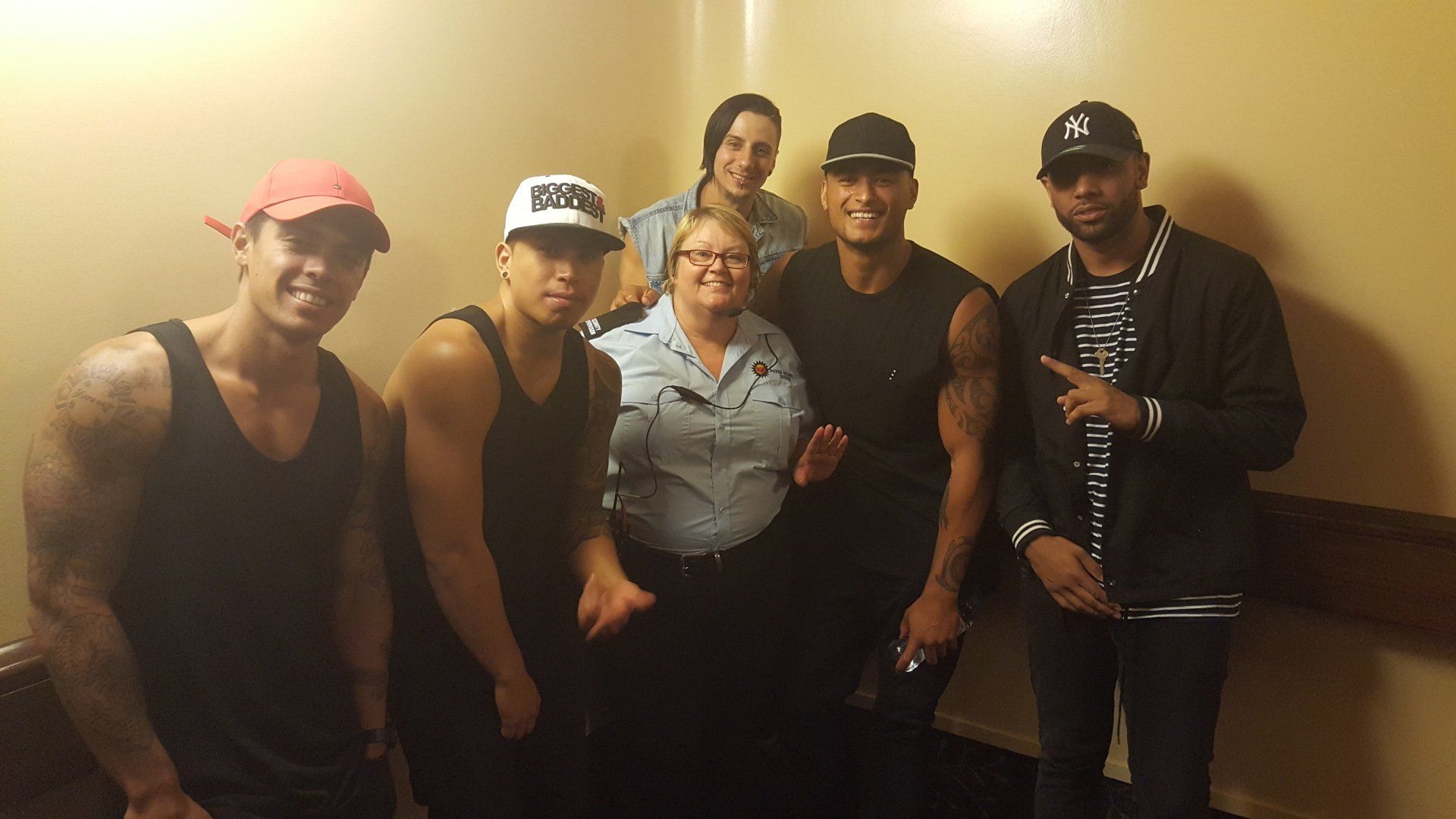 A group of seven people pose for a photo in a hallway.