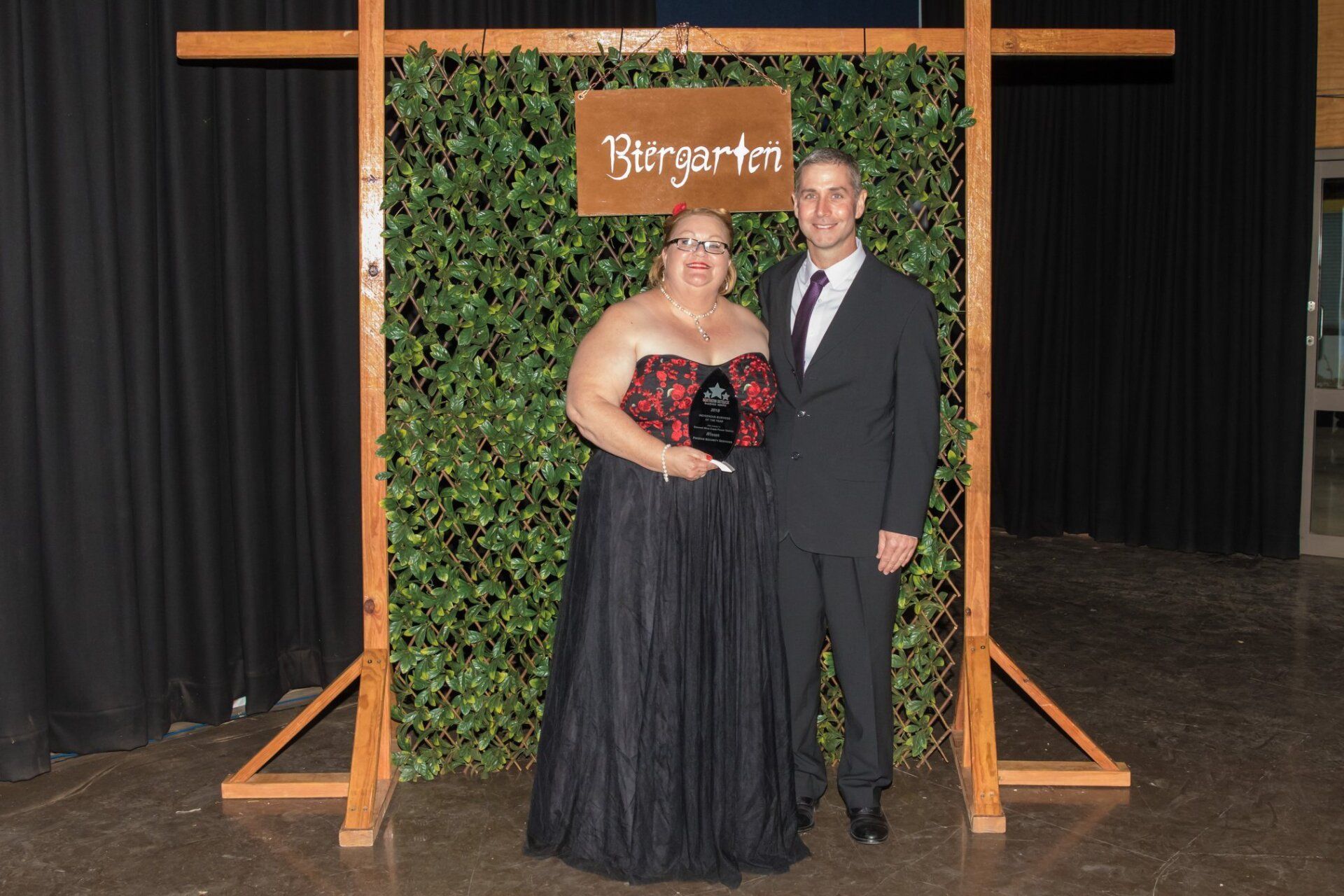 Woman in evening gown and man in suit pose in front of a