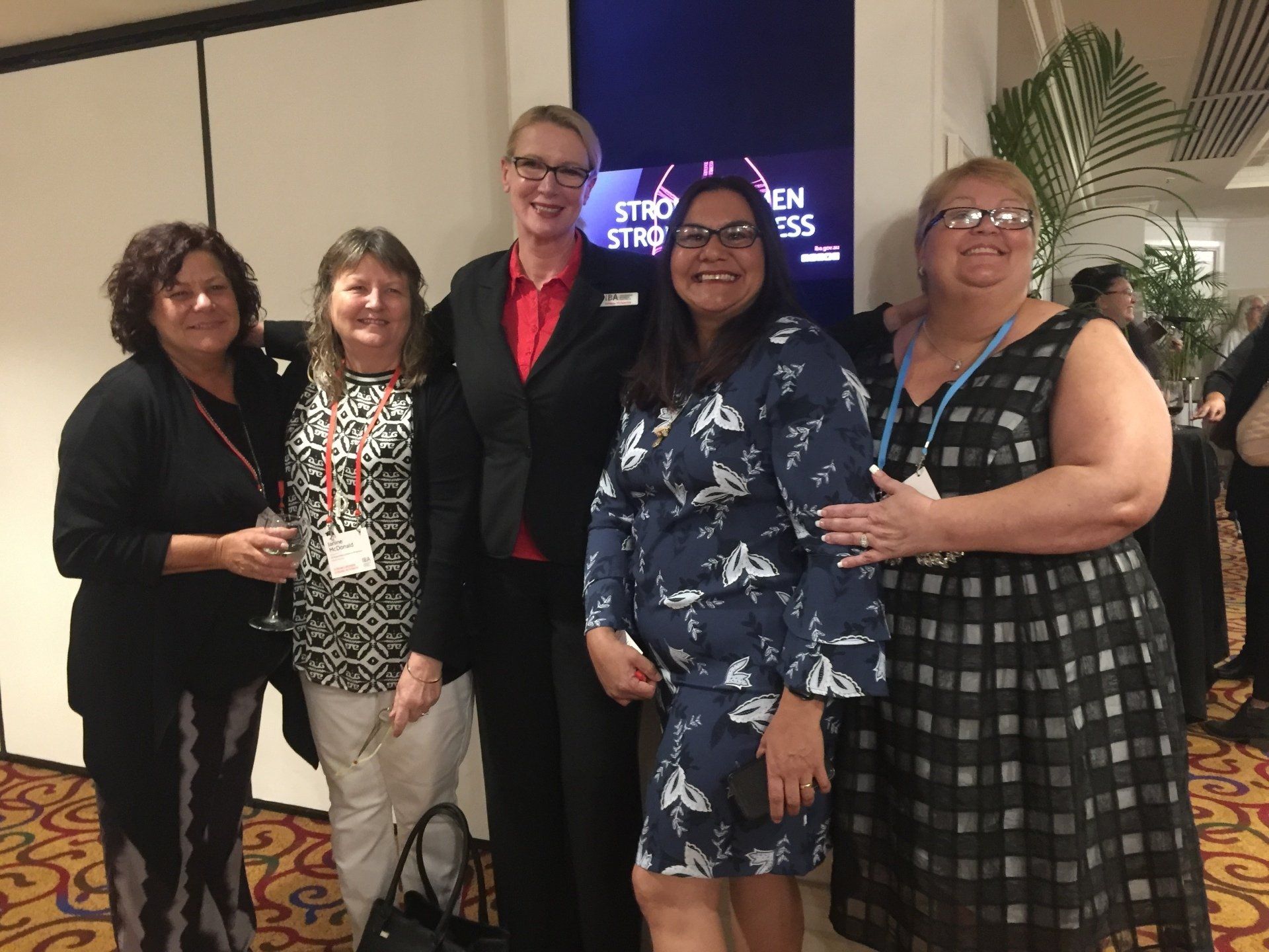 Five women pose at an event