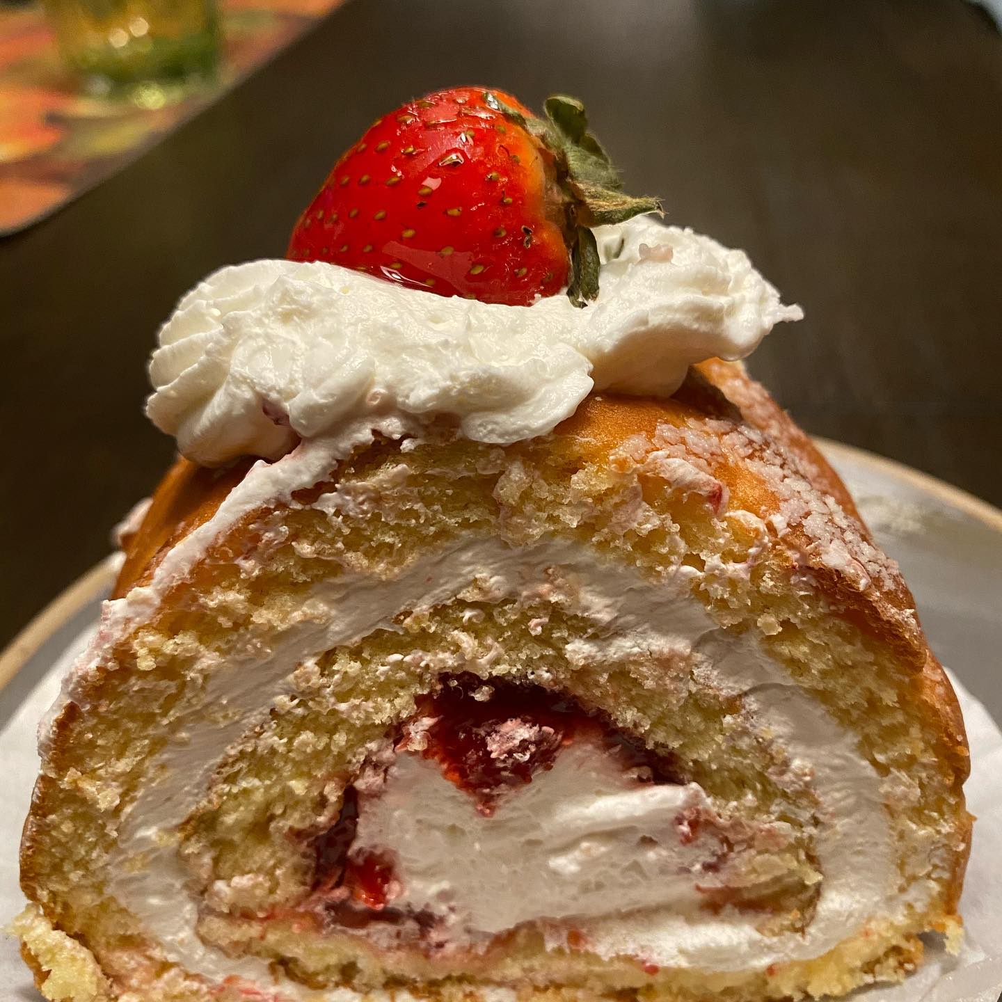 Strawberry swiss roll cake with cream filling and a fresh strawberry on top.