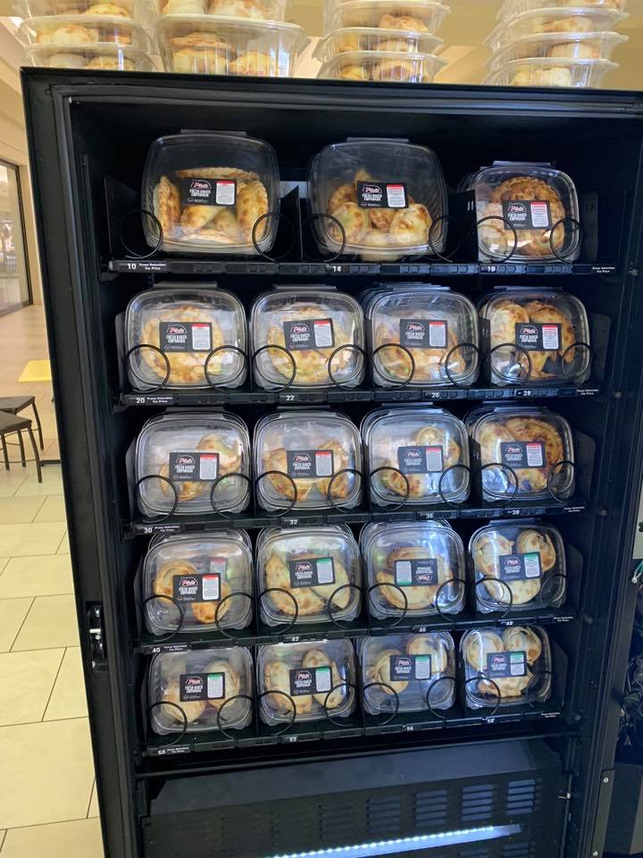 A black refrigerated display case filled with packaged baked goods.