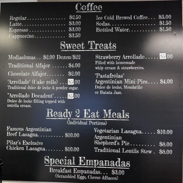 Menu board with coffee, sweets, ready-to-eat meals, and empanadas listed with prices.