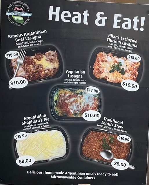Menu board: Heat & Eat meals. Lasagnas, Shepherd's pie, and lentil stew in microwaveable containers. Price range $8-$18.