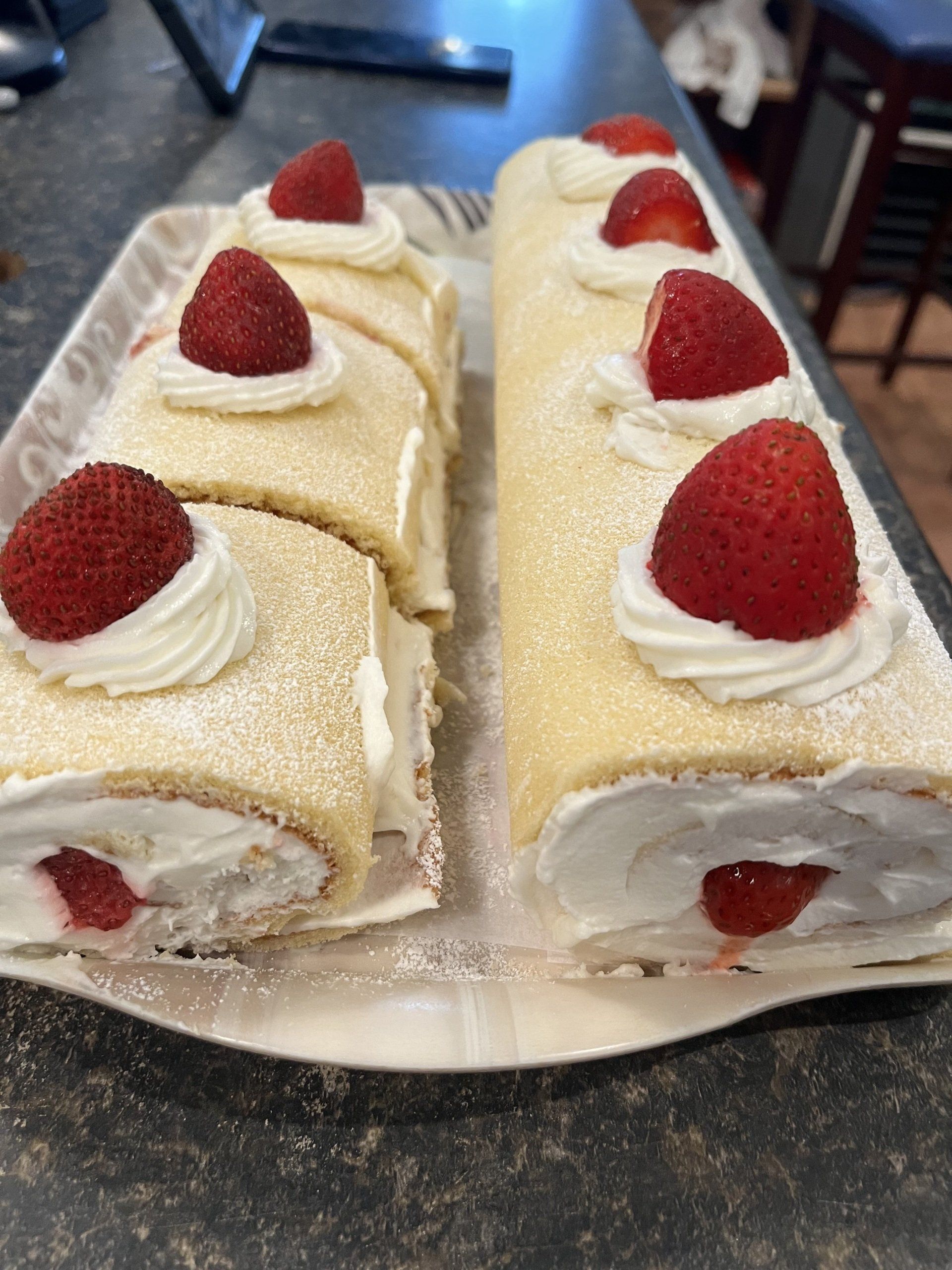 Strawberry cake rolls with whipped cream and fresh strawberries on a platter.