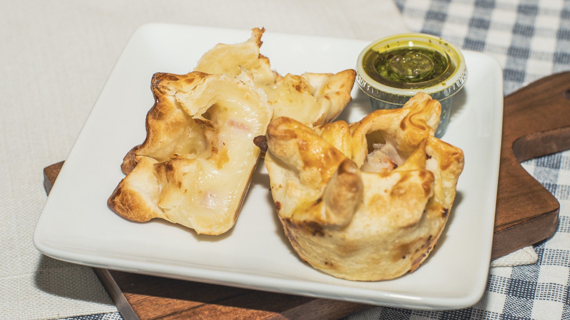 Mini baked pastries with cheese and sauce on a white plate.
