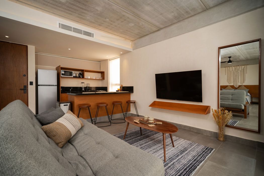 Una sala de estar con un televisor de pantalla plana en la pared y un ventilador de techo.