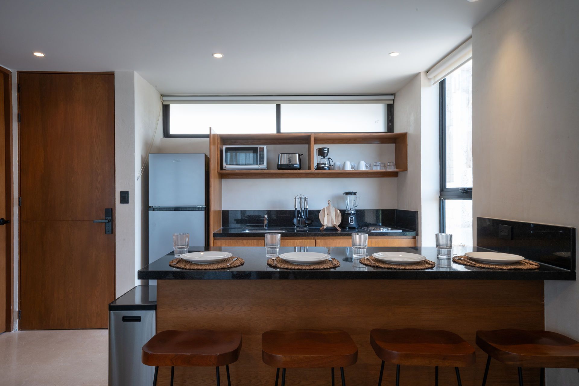 Una cocina con una mesa de comedor y taburetes y un refrigerador.