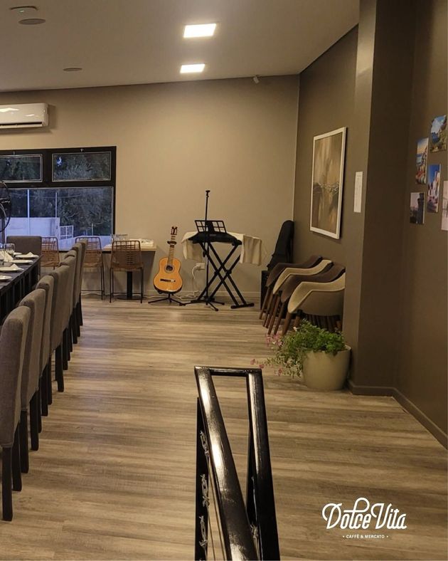 Salón de eventos moderno con guitarra, teclado, sillas y suelo de madera.