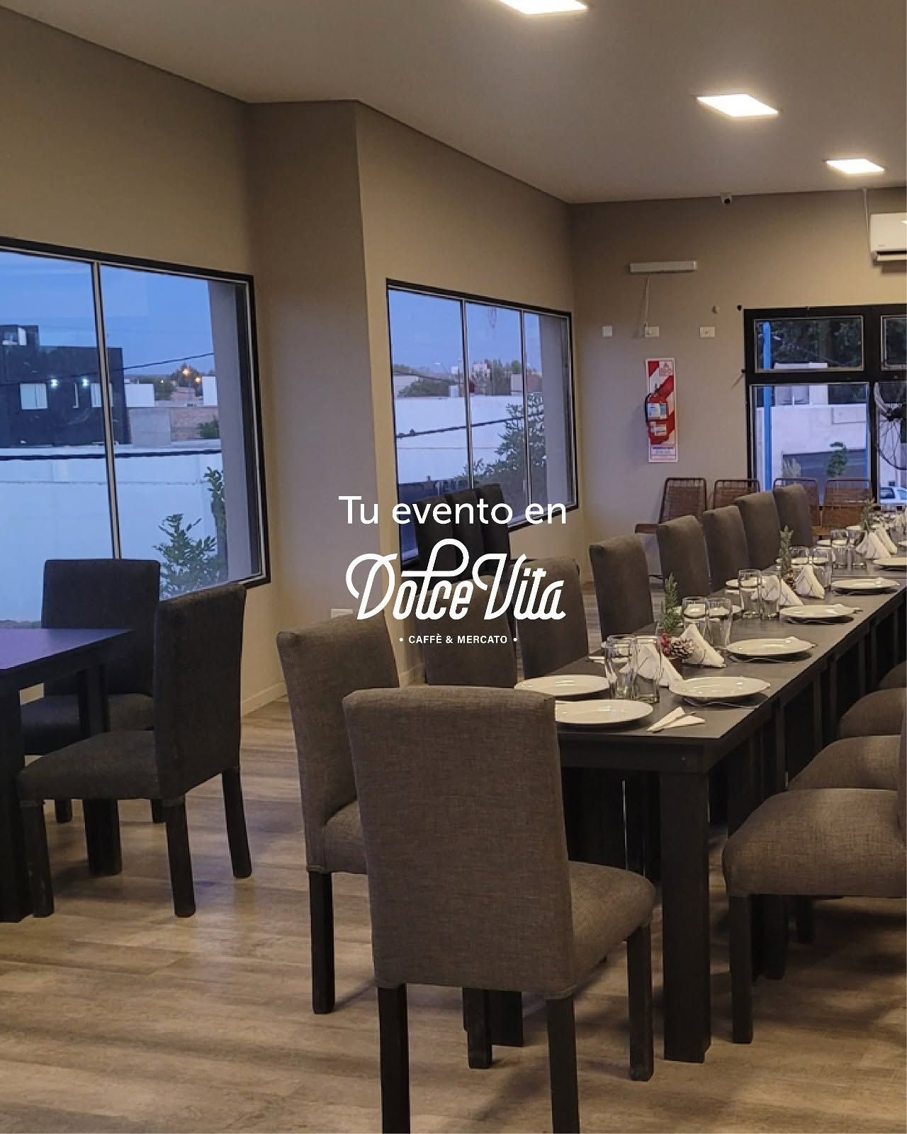 Elegante comedor de restaurante con mesas puestas, sillas beige y grandes ventanales con vistas al exterior nevado.