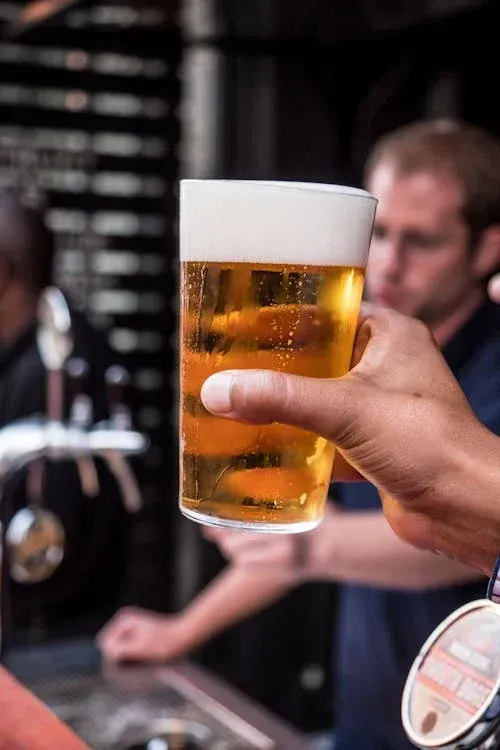 A person is holding a glass of beer in their hand.