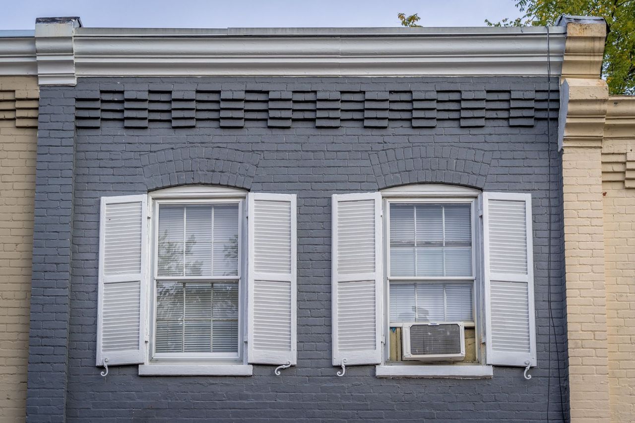 A brick building with white shutters on the windows