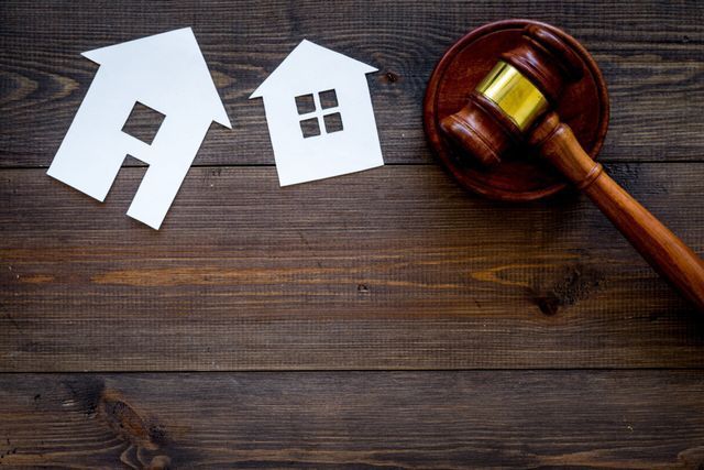 A wooden judge 's gavel is sitting on a wooden table next to paper houses.
