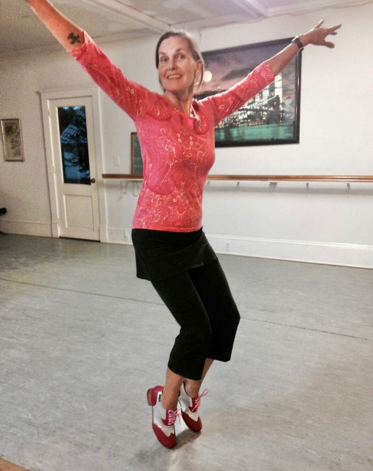 a woman in a pink shirt and black pants is dancing