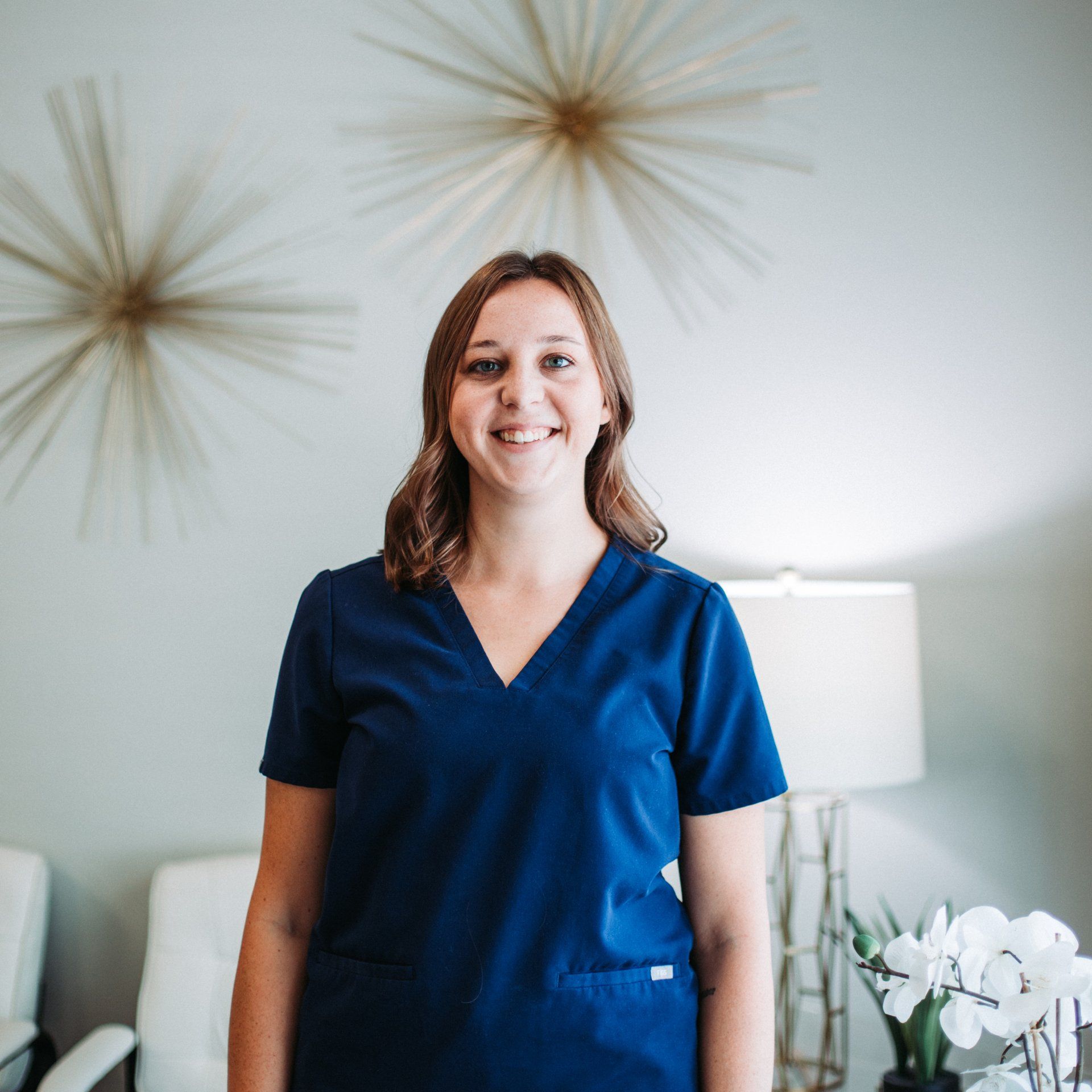 a woman in a blue scrub top is smiling in a room .