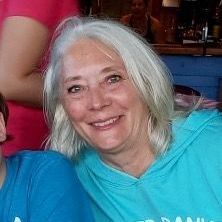A woman with white hair is smiling for the camera while wearing a blue shirt.