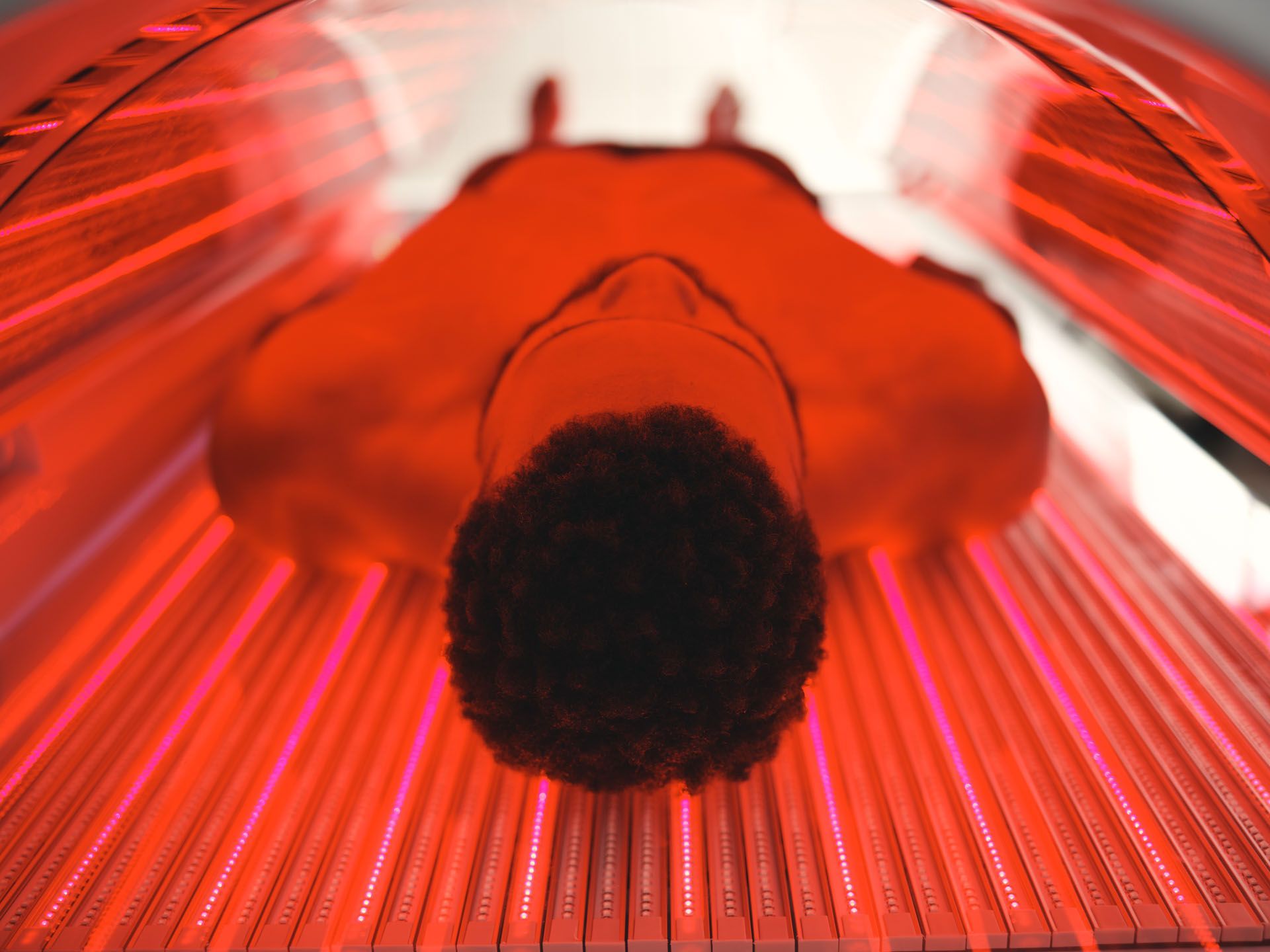 Person inside a red tanning bed with glowing red lights