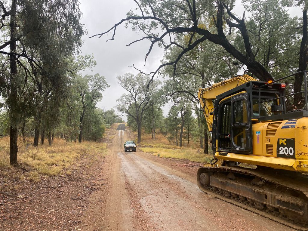 A yellow bulldozer is driving down a dirt road.