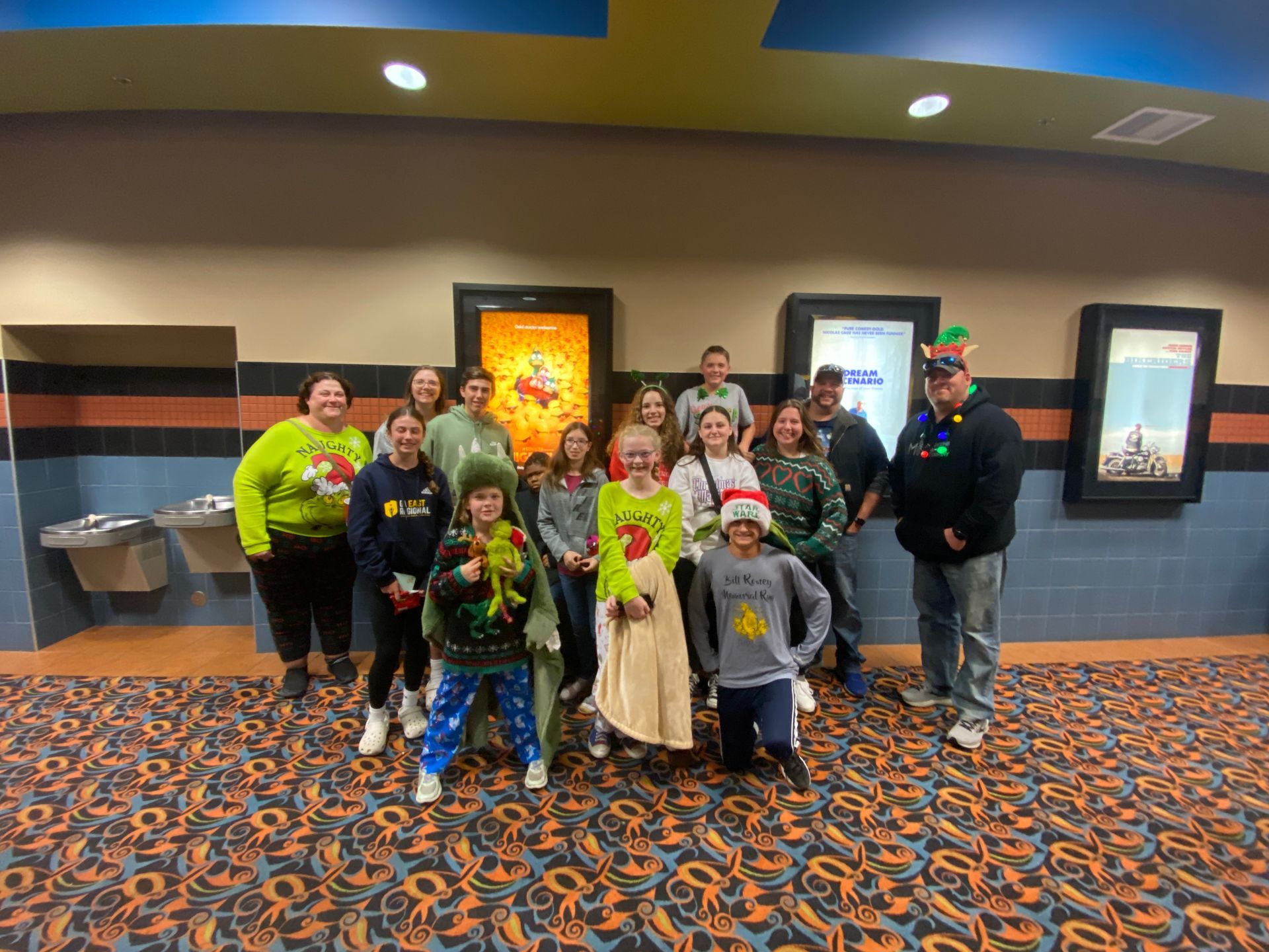 Group of people in festive attire posing inside a movie theater.