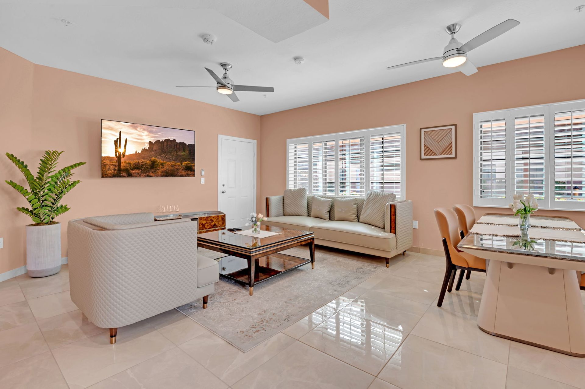 Living room with coral walls, neutral furniture, and a desert landscape on TV.