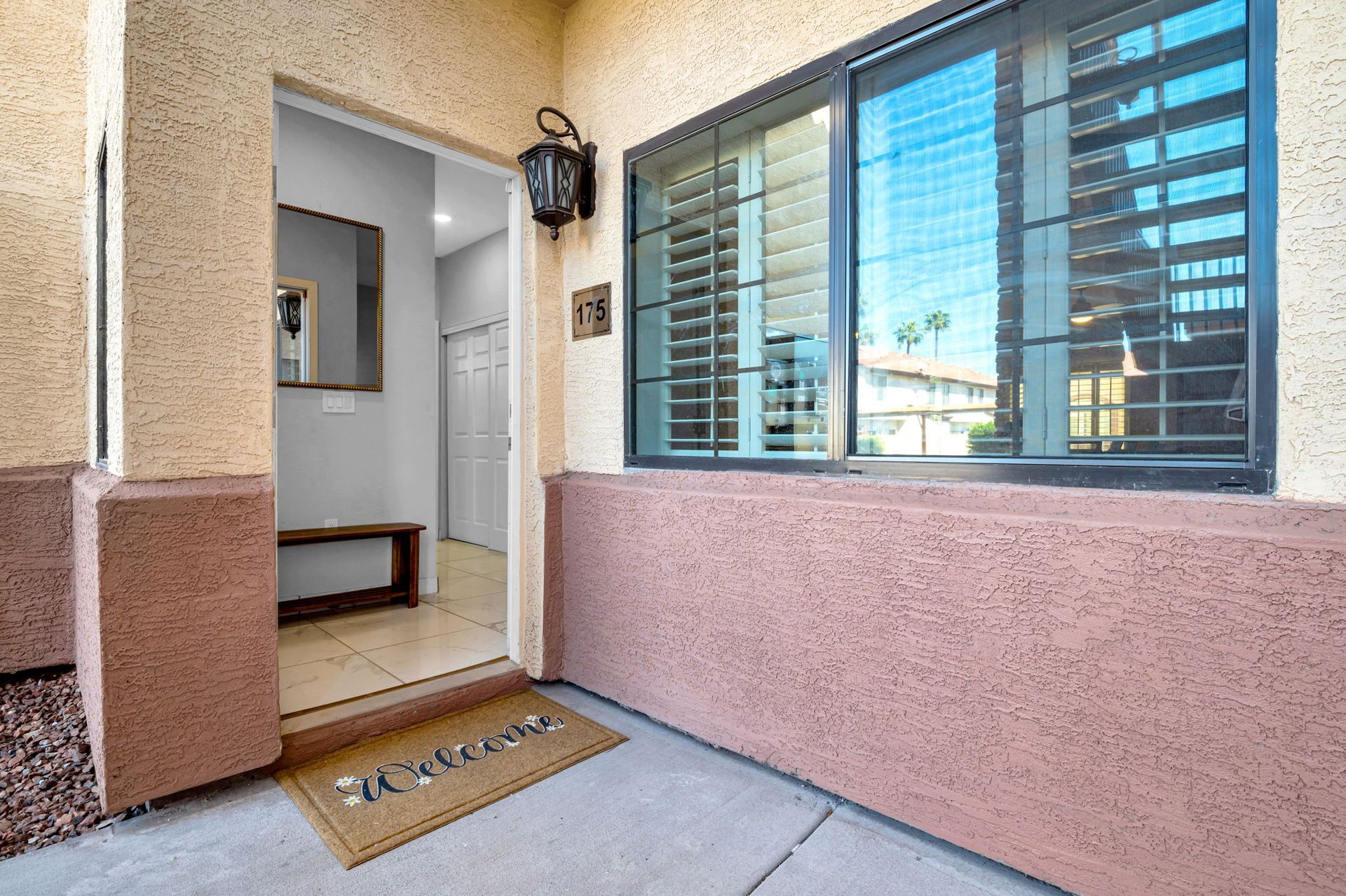 Exterior entryway of a home, featuring a door, window, and welcome mat.