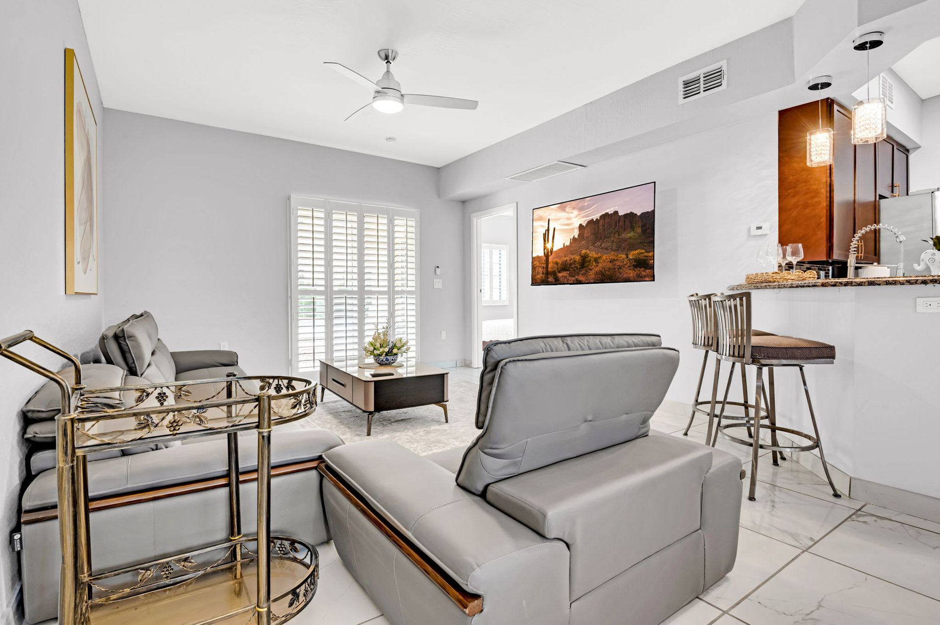 Modern living room with grey furniture, bar, and large screen TV.