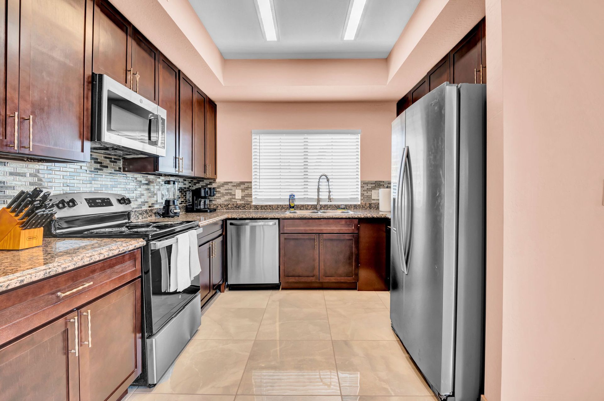Kitchen with dark wood cabinets, stainless steel appliances, granite countertops, and tile floor.