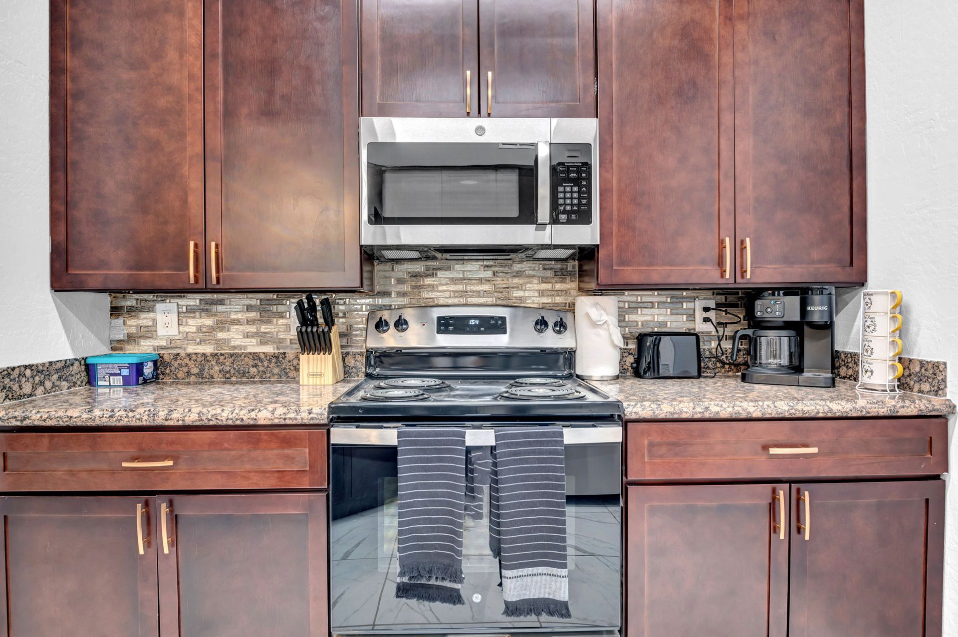 Kitchen with dark brown cabinets, stainless steel appliances, and granite countertops.