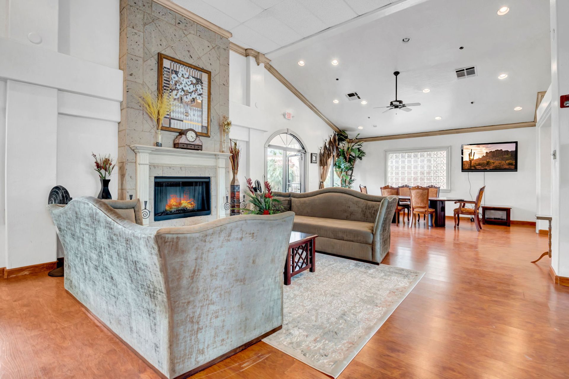 Living room with fireplace, sofas, dining area, and tan walls.