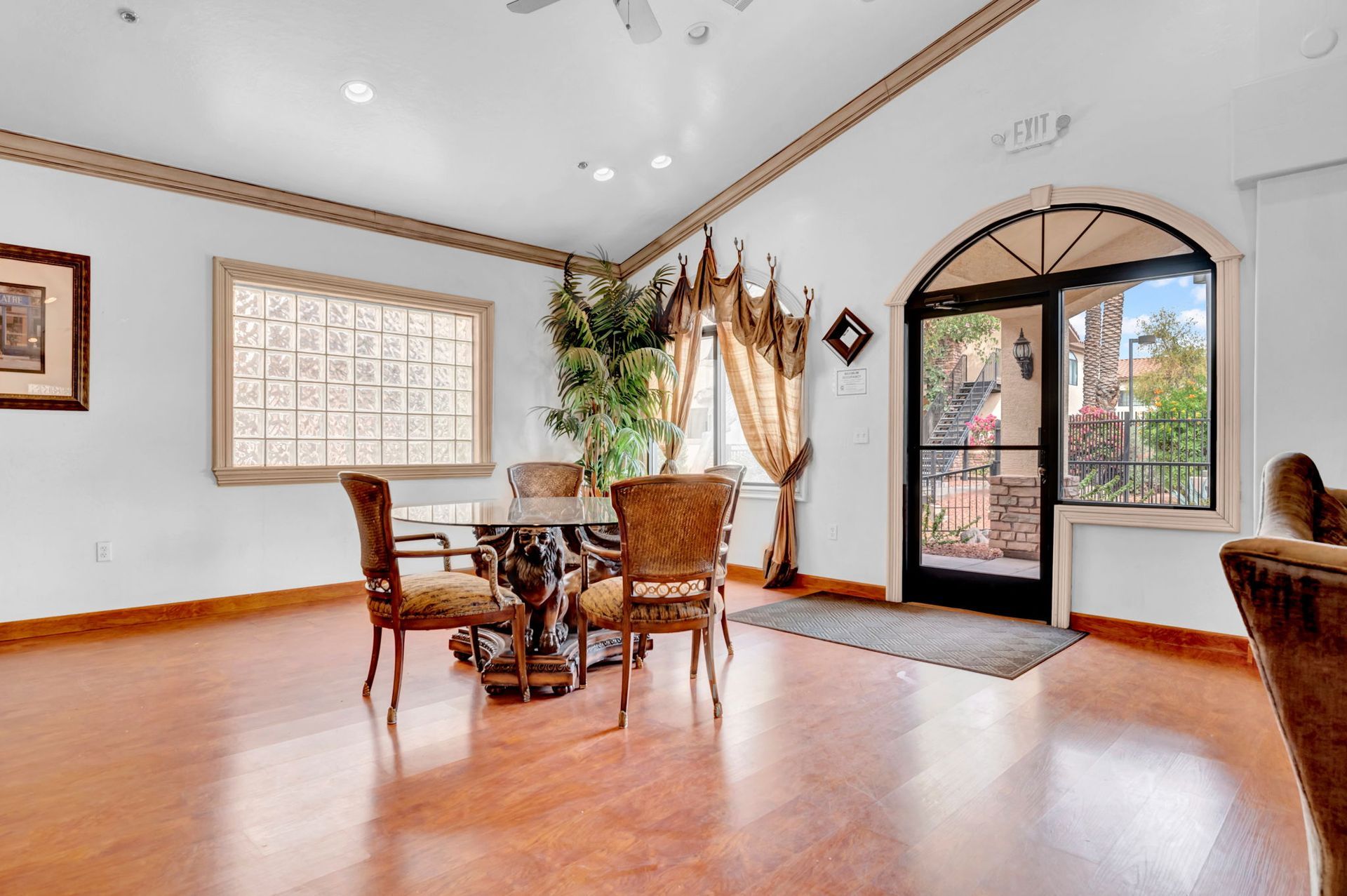 A dining area with a round table, chairs, large window, and arched doorway to an outdoor balcony.