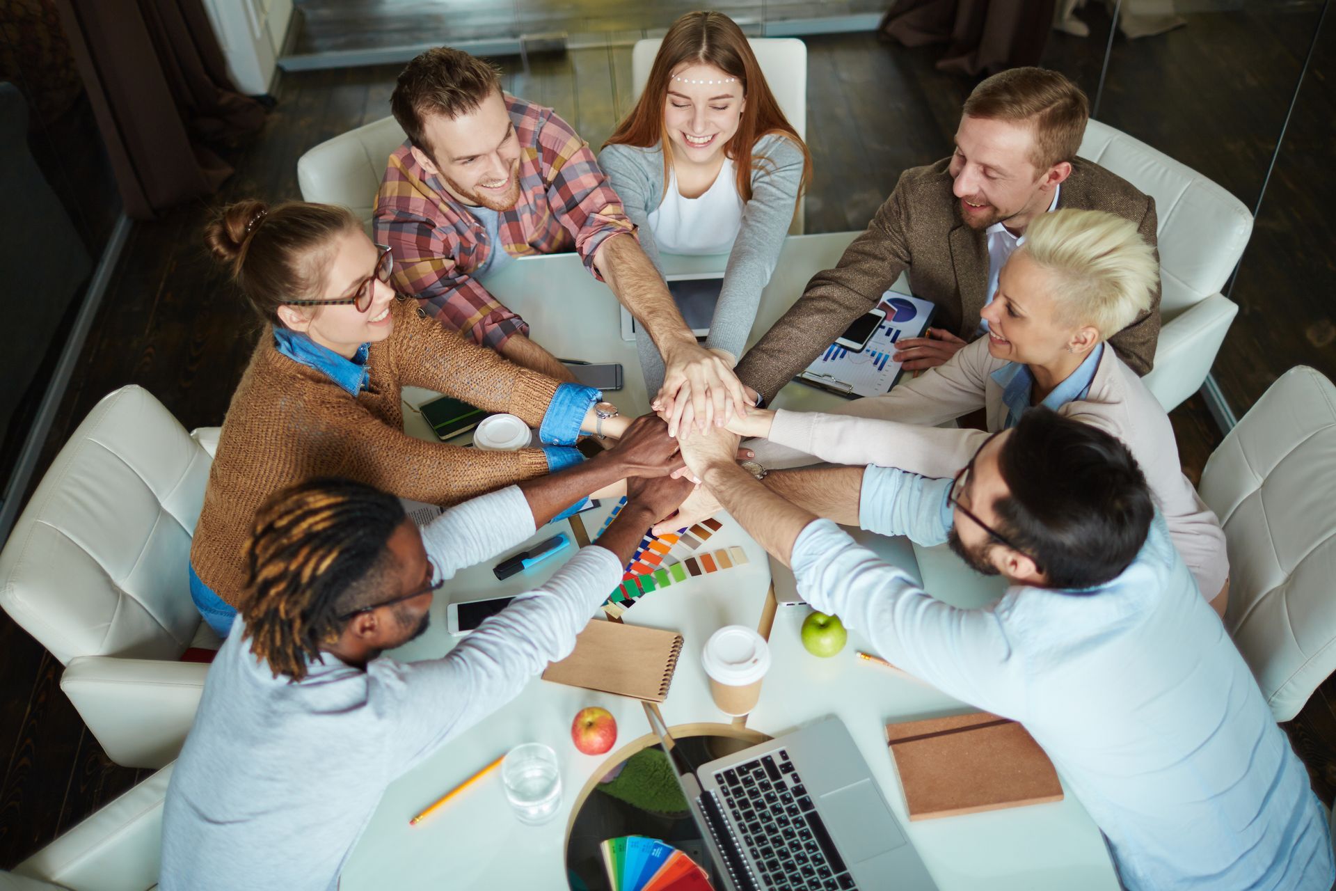Group of people are putting their hands together in a circle.