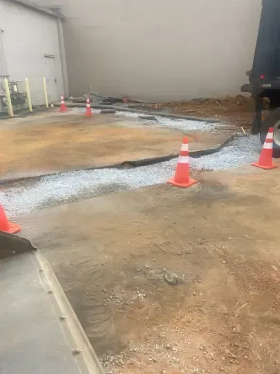 Orange cones marking a damaged concrete floor in a warehouse-like room