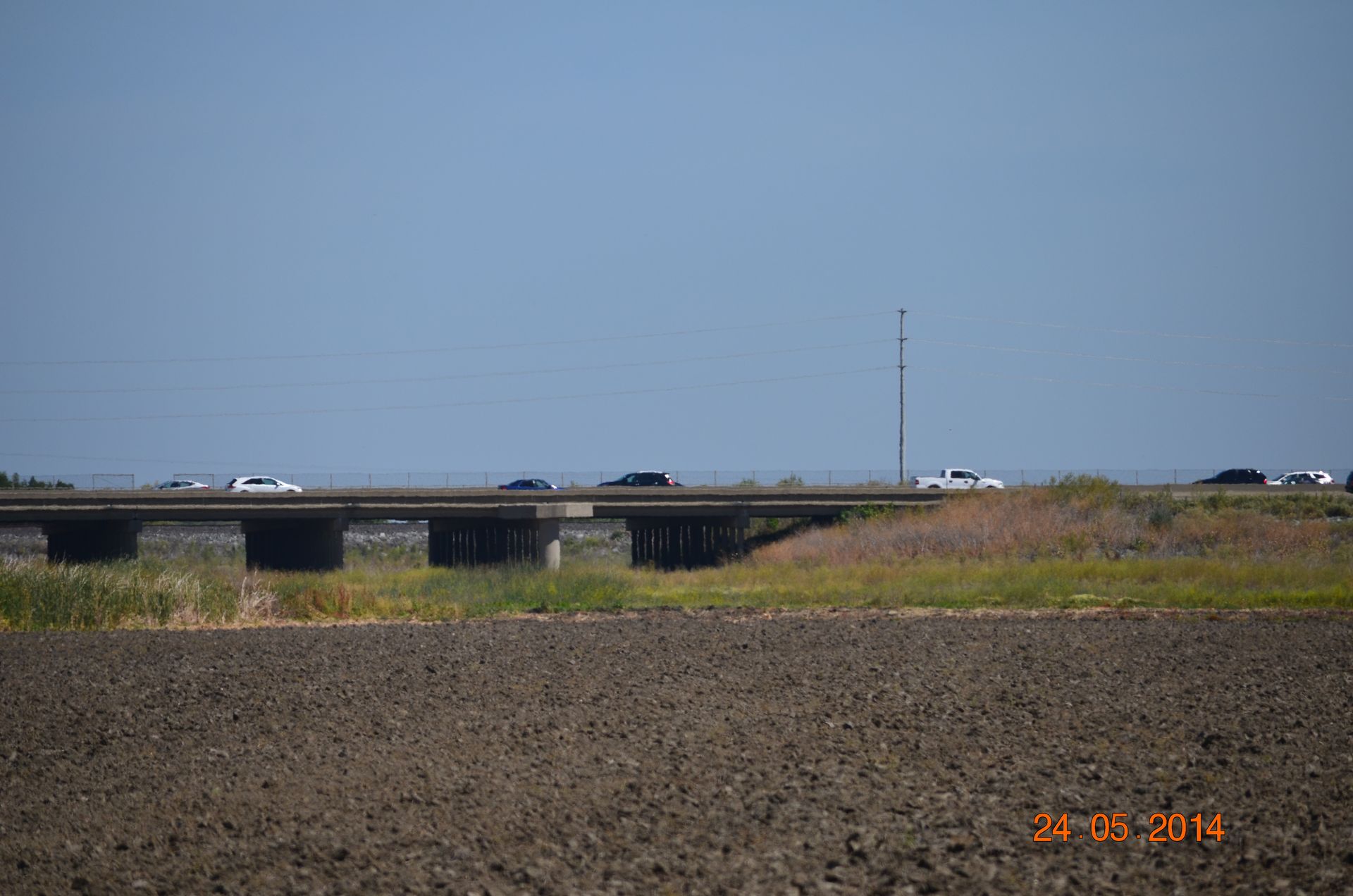 Highway bridge over a dry, rocky field under a clear blue sky