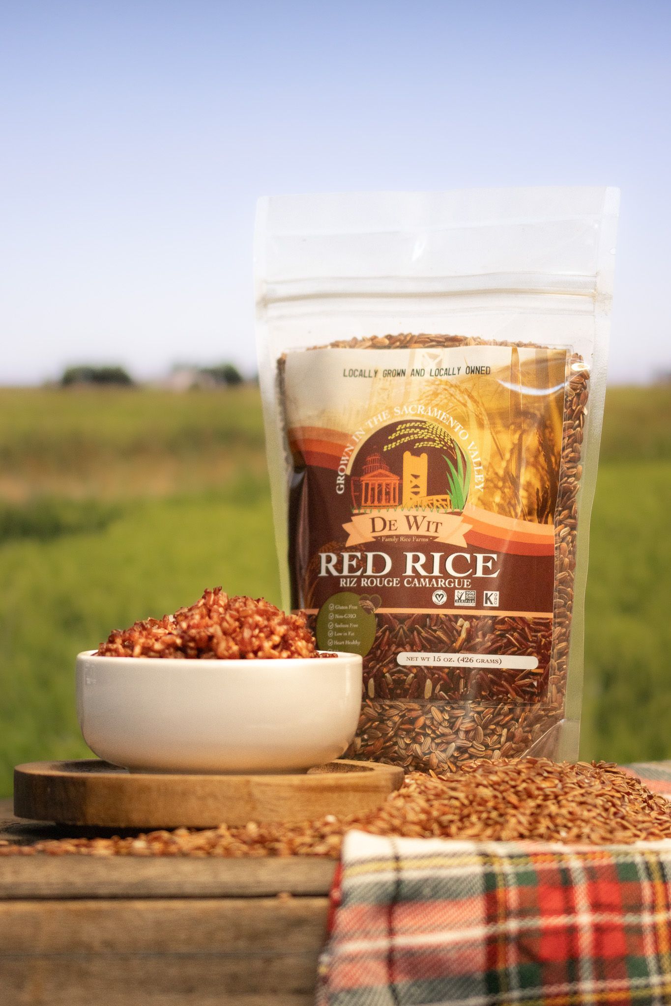 Hands holding red and white rice grains over a grain pile background