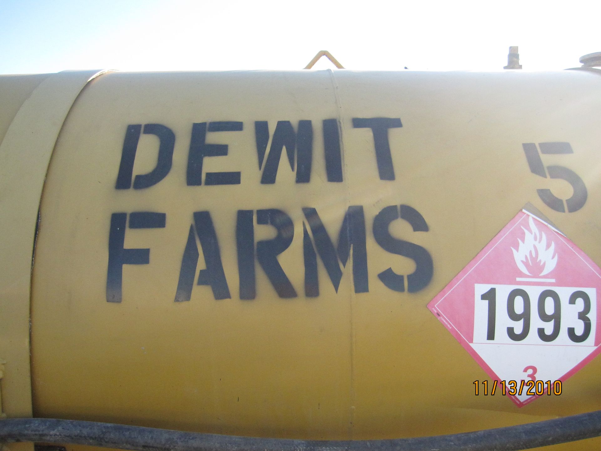 Yellow tank labeled “DEWIT FARMS” with a pink “1993” hazard placard.