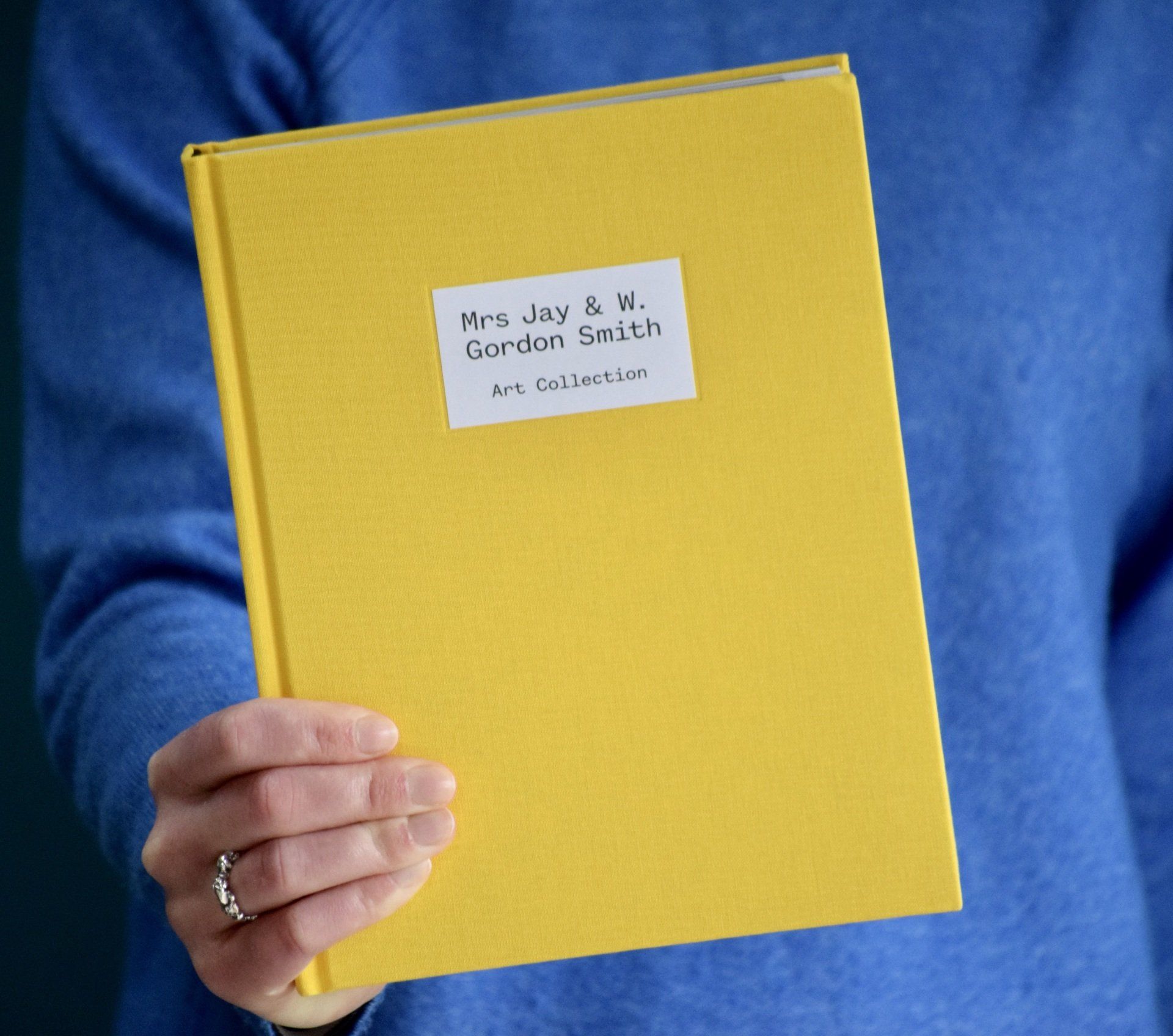 Photo of yellow book being held in front of blue background