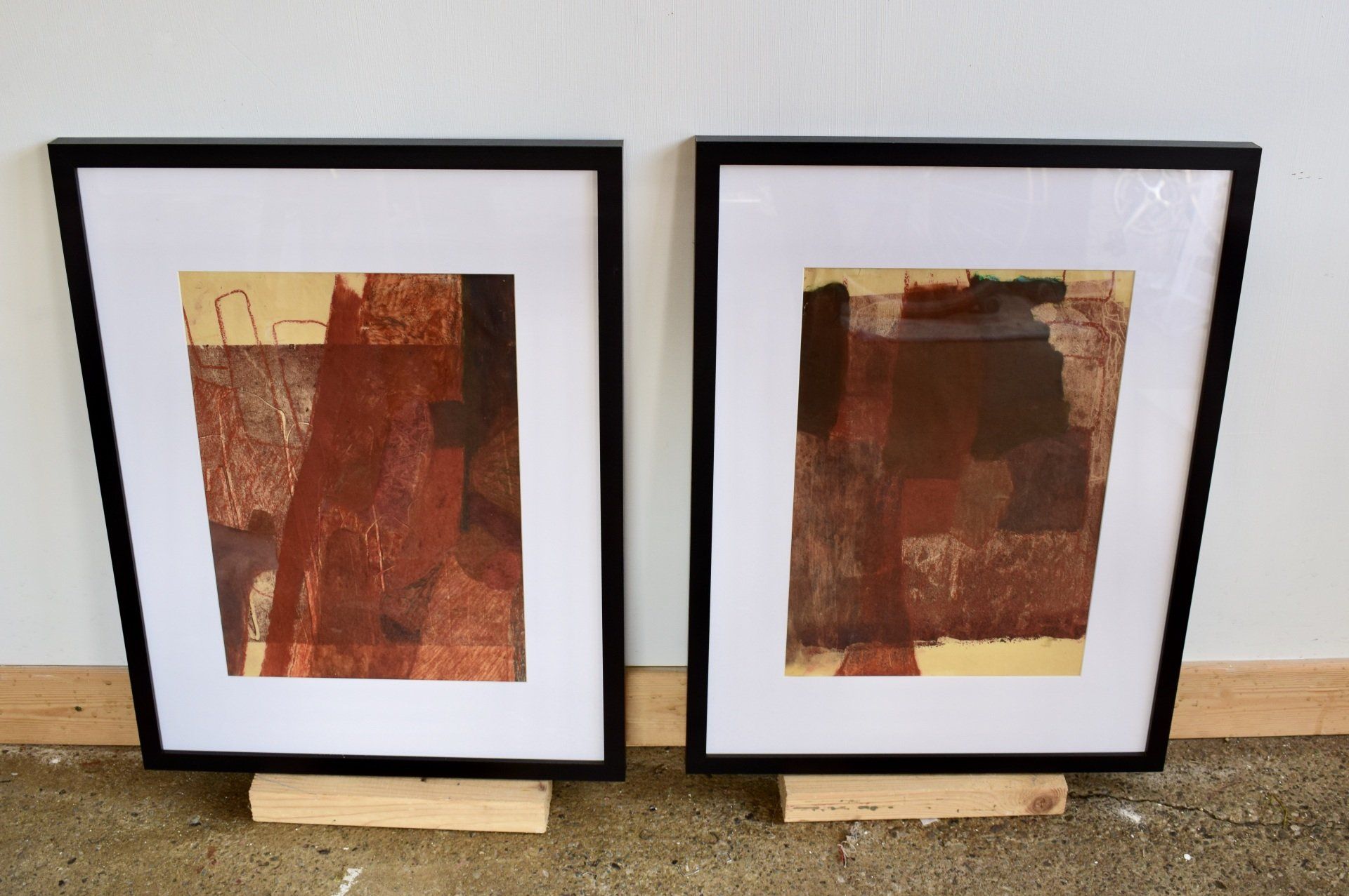 Photo of two framed drawings leaning against white wall