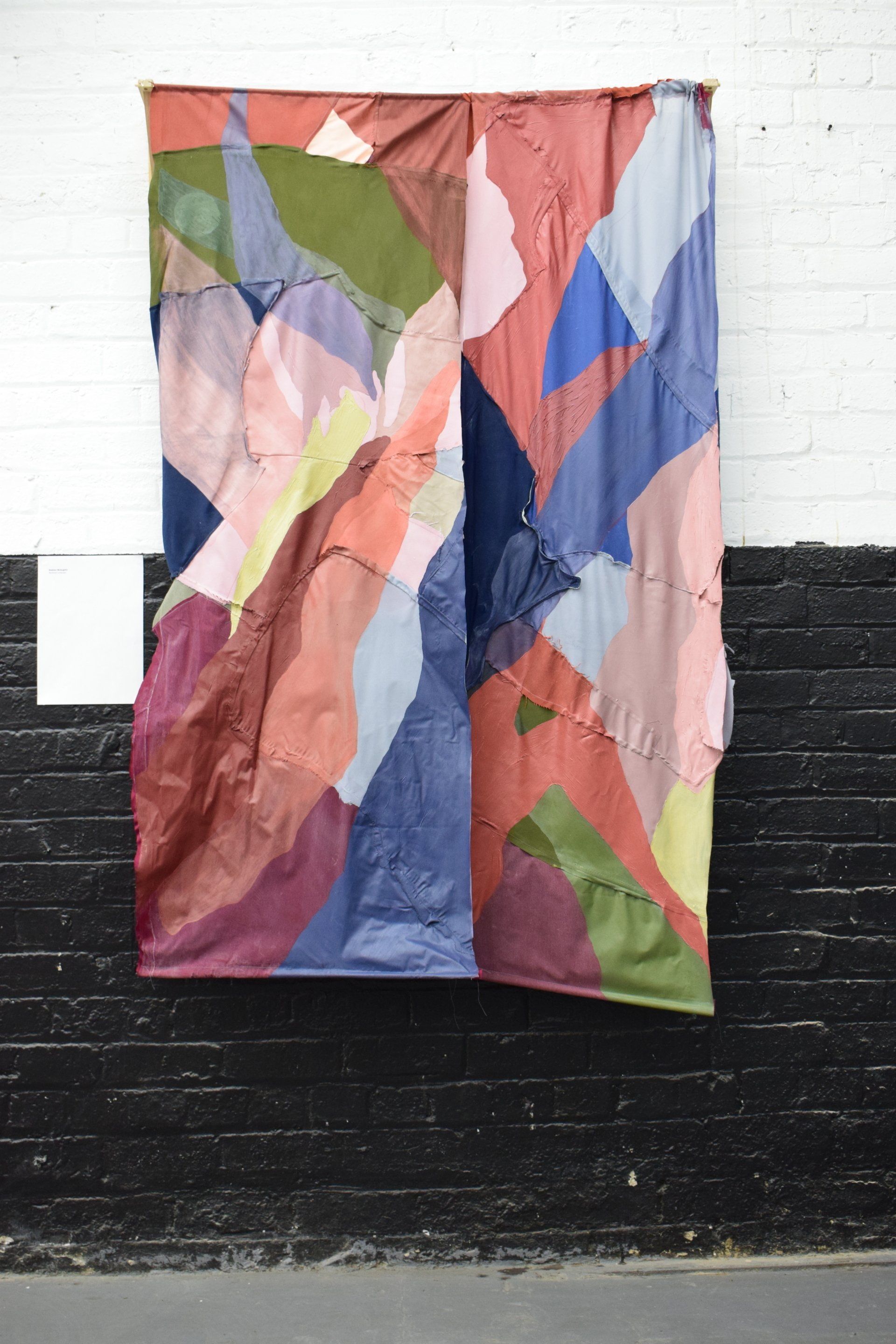 Colourful abstract paintings hanging on white gallery wall