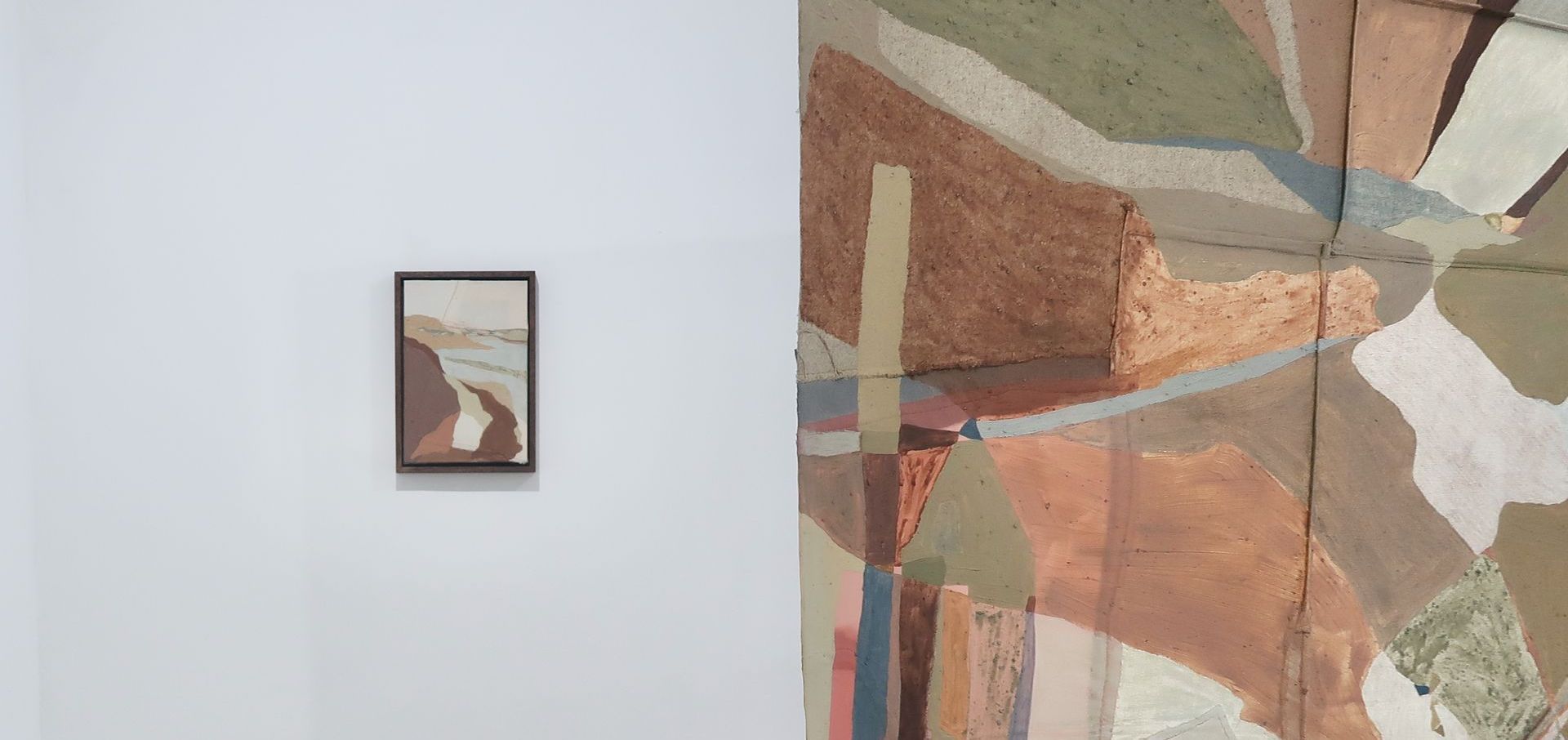 Two colourful abstract landscape paintings on a white wall