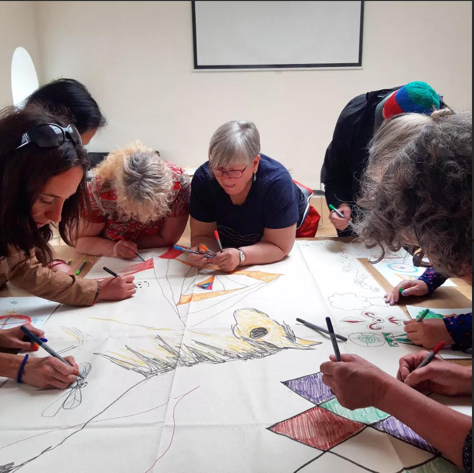 Photo of 6 people leaning on a table to draw