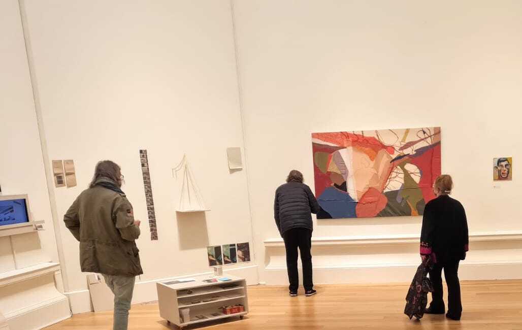 Three people standing in gallery space looking at abstract painting