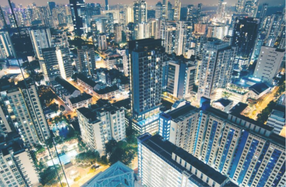 City skyline at night, with illuminated high-rise buildings and bright city lights.