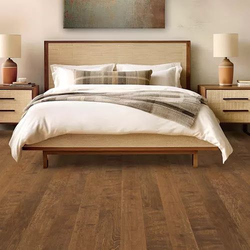 A bedroom with a bed , nightstands , lamps and a painting on the wall.