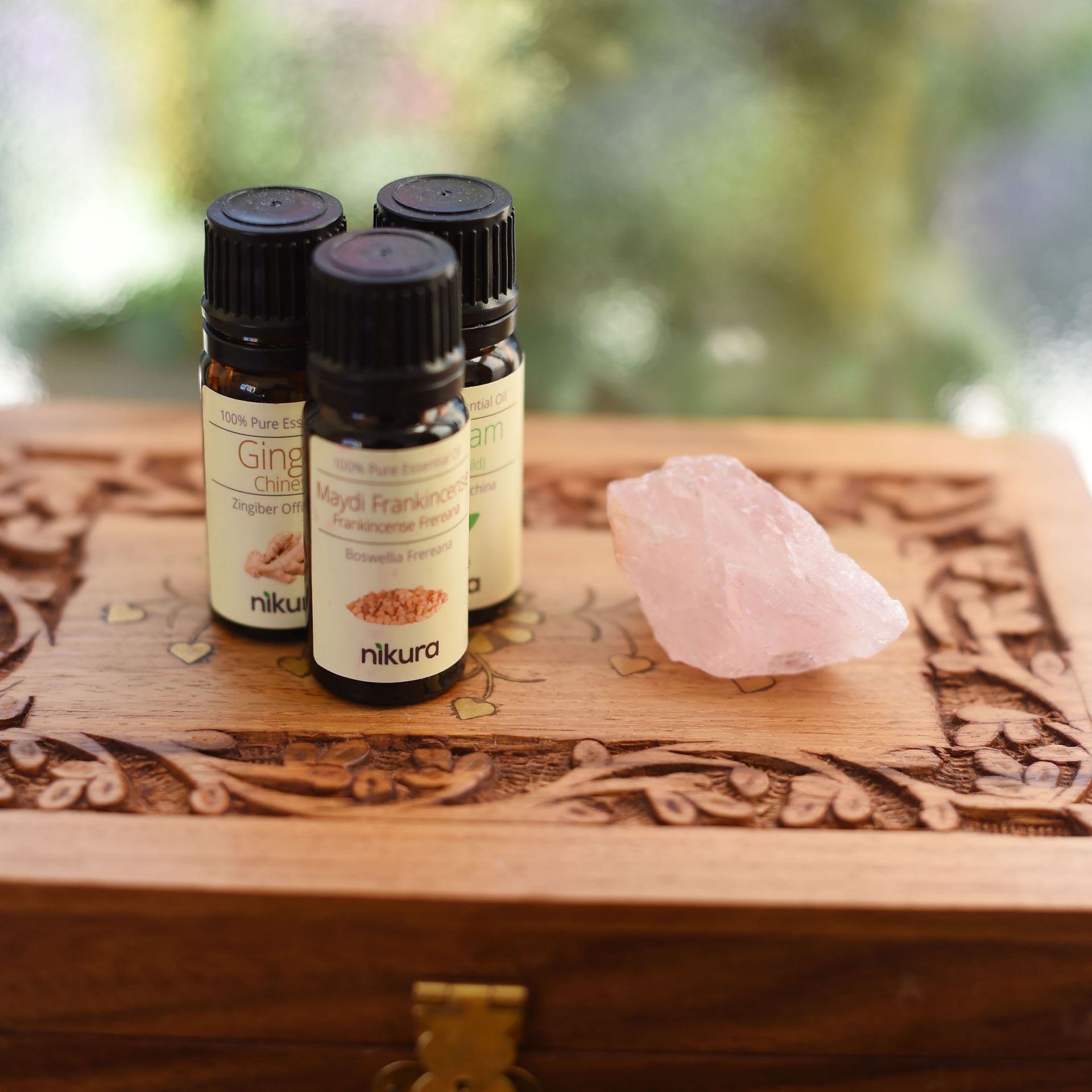 Three bottles of essential oils are sitting on top of a wooden box.